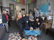 Jenny Thompson, executive director of the Police Activities League of Southwest Washington, from left, helps organize donations for families at Discovery Middle School with Officer Danielle Wass, Lt. Doug Luse and Walmart Neighborhood Market Assistant Manager Leanne Younger before Christmas. Drew Schoening, in black shirt, and David Mack of Walmart Neighborhood Market also helped. The &quot;essentials drive&quot; is one of several holiday events Thompson organizes.