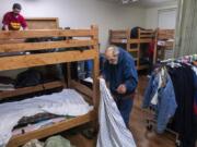 Tyler Taplin, left, and Chad Calhoun make their beds inside the Winter Hospitality Overflow shelter at St. Paul Lutheran Church in downtown Vancouver ahead of a chilly night on Monday. The Vancouver City Council will likely approve a grant that would increase funding to the shelter, allowing operators to keep it open year-round instead of just five months out of the year.