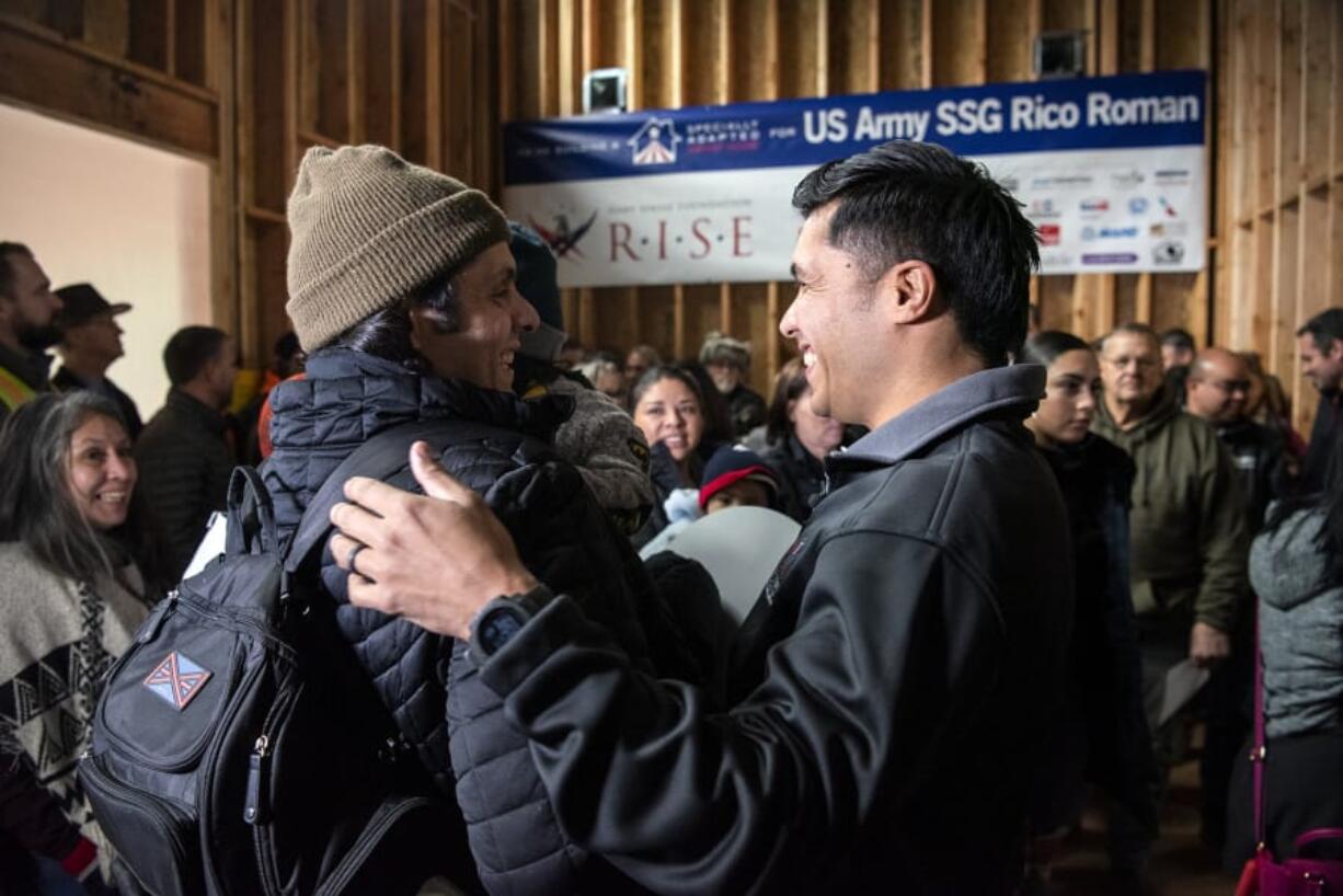 Rico Roman, right, embraces his younger brother, Carlos Roman, during Monday&#039;s &quot;Walls of Honor&quot; event at the home being built for Rico Roman and his family east of Hockinson. The Gary Sinise Foundation, along with other donors, are building a specially adapted smart home for Rico Roman, a retired Army staff sergeant who had his lower left leg amputated after being injured in Iraq.