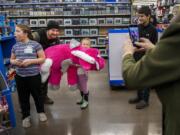 Faith Stanchfield, 6, center, smiles behind a plush, winged unicorn she picked out Saturday with Cowlitz County Sheriff&#039;s Deputy Craig Murray while sister Grace Stanchfield, left, ogles another toy during Woodland&#039;s annual &quot;Shop with a Cop&quot; event at Walmart in Woodland.