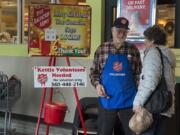 Bruce Davis of Vancouver, left, greets shopper Myrna Webb of Redmond, Ore., while bell ringing at the Grand Central Fred Meyer on Monday afternoon. Davis has been helping out as a bell ringer for the last 50 years. &quot;It&#039;s actually a lot of fun. I enjoy it,&quot; he said.