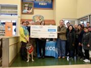 CASCADE PARK WEST: Dr. Emily Huber is with her dog, Woofy, while Dianne McGill, Pet Peace of Mind founder/president, middle, and Dr. Bob Lester, Pet Peace of Mind board of directors and chief medical officer at WellHaven Pet Health, right, hold the check. WellHaven Pet Health employees and Pet Peace of Mind supporters joined in at the Dec. 17 event at Petco, 305 S.E.