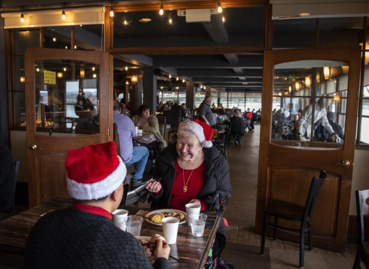 Peter Blanco, left, and his wife Susan, right, enjoy the annual free Christmas Day meal together at WareHouse &#039;23 in Vancouver. &quot;We&#039;re both disabled and preparing meals is sometimes difficult,&quot; Susan Blanco said. &quot;We&#039;re very grateful for the people who give up their Christmas Day.&quot; The meal is organized by WareHouse &#039;23 owner Mark Matthias, state Court of Appeals Judge Rich Melnick, and Chuck Chronis, who previously hosted it at his downtown Vancouver bar.