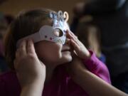 Jasmina Hakanovic helps her daughter Zara, 3, both of Camas, put on a decorated mask during the Noon Year&#039;s Eve Party at the Camas Public Library.