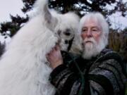 Caesar the No Drama Llama cuddles with Larry McCool at Mystic Llama Farm in December 2019 in Jefferson, Ore.