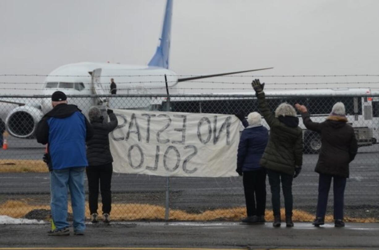 Activists in Yakima wave encouragement to a detainee in shackles boarding a U.S. Immigration and Customs Enforcement flight bound for Mesa, Arizona. ICE moved the flights to the Central Washington city in May after King County officials booted them from Boeing Field near Seattle, saying deportations raised troubling human rights concerns.