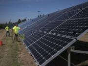 Nick Neathamer, left, and Rafer Stromme, members of the student grounds crew, clean solar panels at Clark Public Utilities in 2019. The panels need to be cleaned to remove dust to maximize energy production.