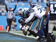 Seattle Seahawks running back Chris Carson scores a touchdown while Carolina Panthers outside linebacker Shaq Thompson (54) tackles during the second half of an NFL football game in Charlotte, N.C., Sunday, Dec. 15, 2019. Seattle Seahawks offensive tackle Duane Brown (76) assists at right.