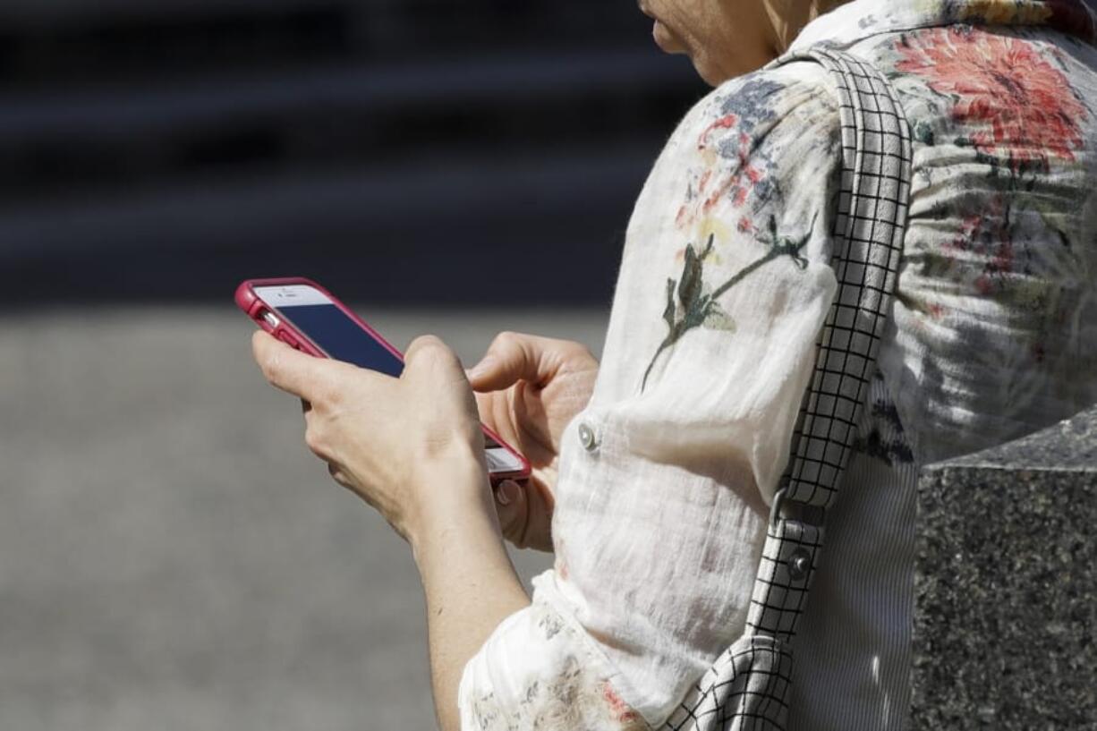 FILE - In this April 8, 2019, file photo, a woman browses her smartphone in Philadelphia. Accidental cuts and bruises to the face, head and neck from cellphones are sending increasing numbers of Americans to the emergency room, according to a study that estimates 76,000 cases over nine years.