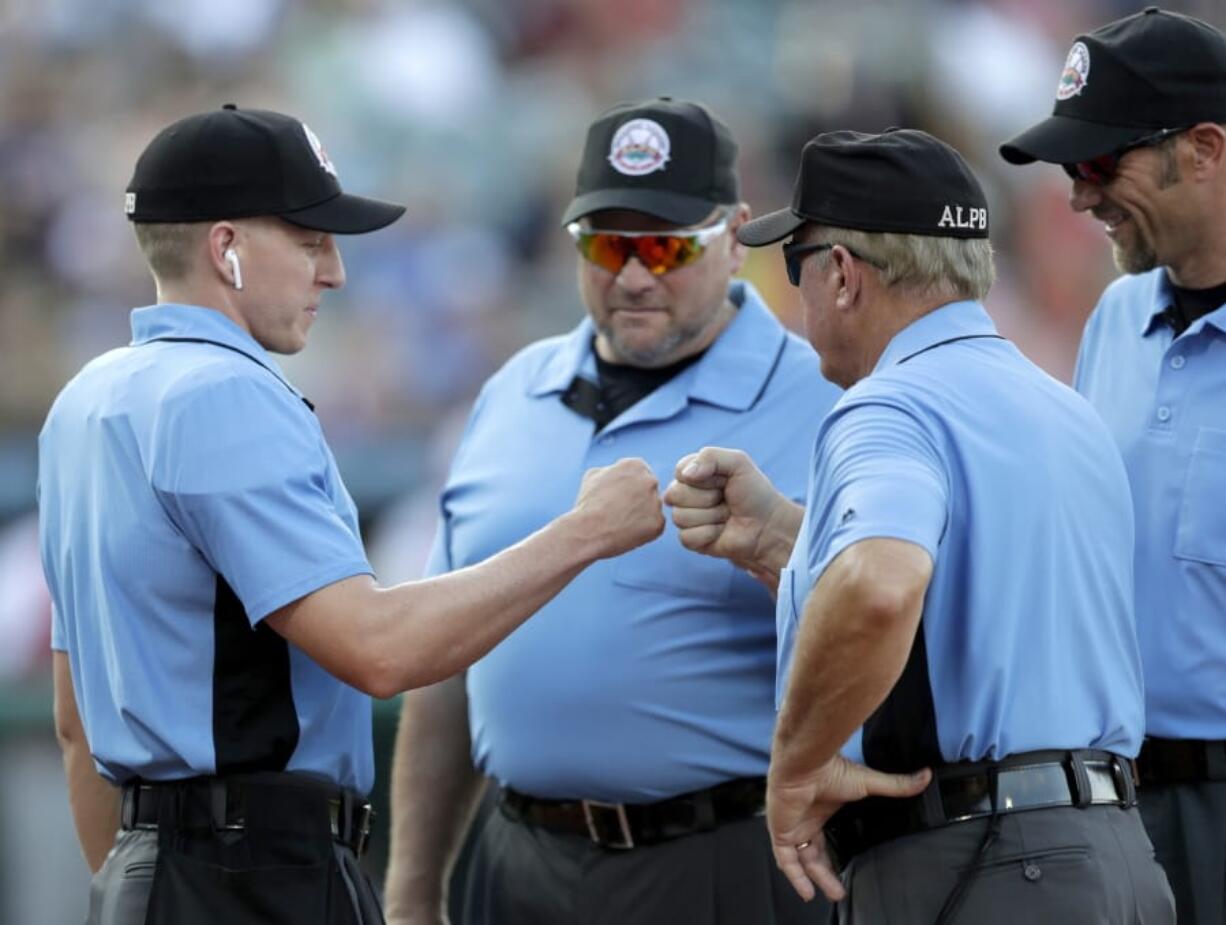 Home plate umpire Brian deBrauwere, left, huddles with officials while wearing an earpiece connected to a ball and strikes calling system before the Atlantic League All-Star minor league baseball game in York, Pa., on July 10, 2019.