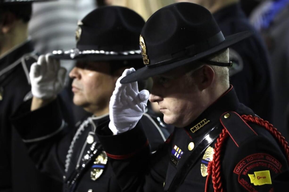 A Washington state Department of Corrections officer salutes Monday during the memorial service for Pierce County Sheriff&#039;s Deputy Cooper Dyson in Tacoma. (Ted S.