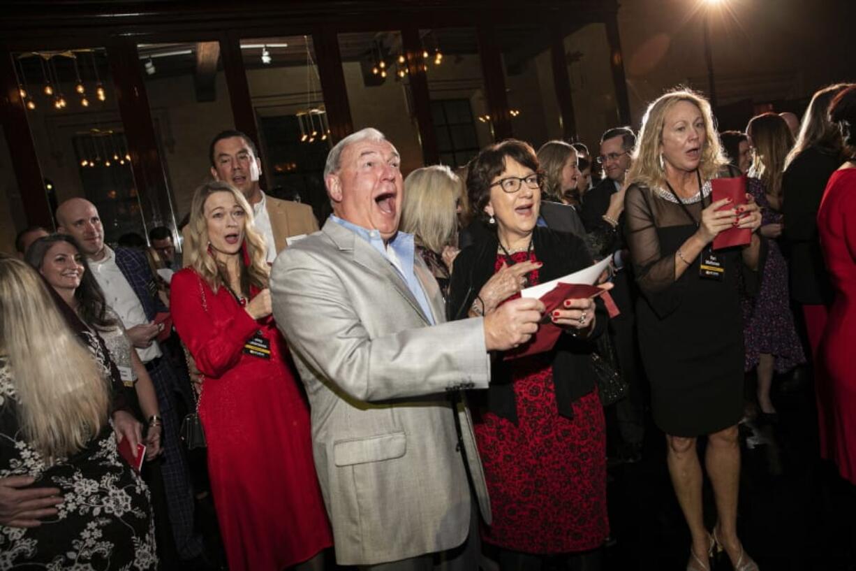 In this image released by St. John Properties, employees of the Maryland real estate firm react after finding out the company is surprising them with $10 million in bonuses at a holiday party, Saturday, Dec. 7, 2019, in Baltimore.