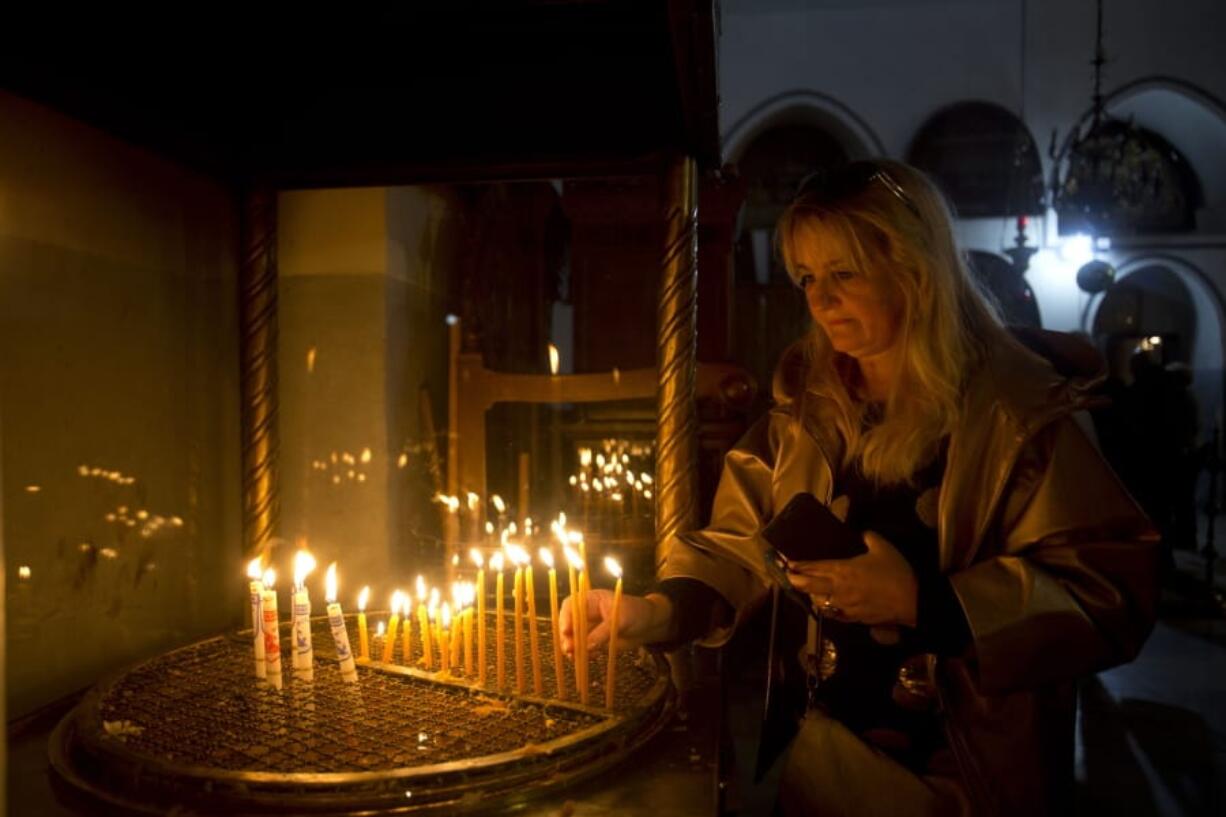 A visitor lights a candle at the Church of the Nativity built on top of the site where Christians believe Jesus Christ was born on Christmas Eve, in the West Bank City of Bethlehem, Tuesday, Dec. 24, 2019.