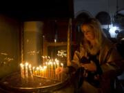 A visitor lights a candle at the Church of the Nativity built on top of the site where Christians believe Jesus Christ was born on Christmas Eve, in the West Bank City of Bethlehem, Tuesday, Dec. 24, 2019.