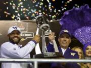 Jimmy Lake, left, Washington defensive coordinator and incoming head coach, and Washington head coach Chris Petersen pose with the Las Vegas Bowl trophy after they defeated Boise State in the Las Vegas Bowl NCAA college football game at Sam Boyd Stadium, Saturday, Dec. 21, 2019, in Las Vegas.