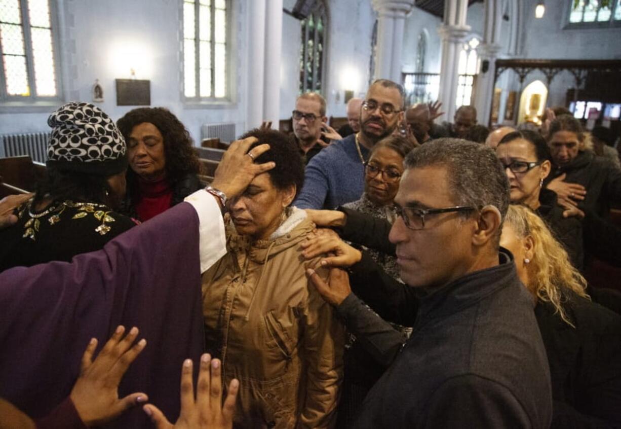 In this Sunday, Dec. 15, 2019, photo, the Rev. Luis Barrios, left, places his hand on the head of Mercedes Katrocino, center, a deaf congregant, as he and the rest of the congregation pray for Katrocino&#039;s health and failing eyesight at Holyrood Episcopal Church in New York on Sunday, Dec. 15, 2019.