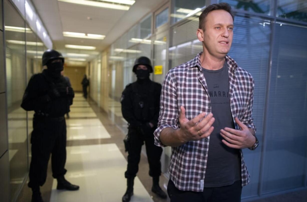 Russian opposition leader Alexei Navalny speaks to the media as policem?n stand guard at the Foundation for Fighting Corruption office in Moscow, Russia, Thursday, Dec. 26, 2019. Alexei Navalny, the most prominent foe of President Vladimir Putin and the governing United Russia party was detained in his office in Moscow.