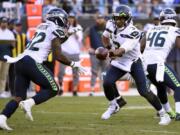 Seattle Seahawks quarterback Russell Wilson (3) hands pff to running back Chris Carson (32) during the second half of an NFL football game against the Carolina Panthers in Charlotte, N.C., Sunday, Dec. 15, 2019.