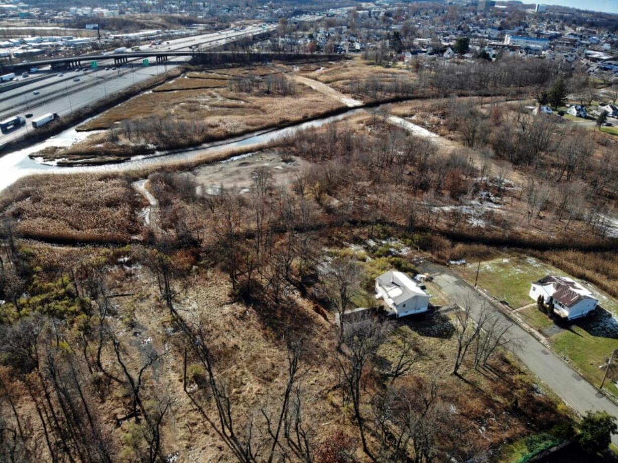 A flood-plain forest grows now where there used to be houses in the Watson Crampton neighborhood in Woodbridge, N.J., as seen from the air on Thursday, Dec. 5, 2019. The Heards Brook on the top meets the Woodbridge River on the left, which leads to the Atlantic Ocean. Homeowners here took buyouts through a program that purchases houses and demolishes them to remove people from danger and to help absorb water from rising sea levels due to climate change.