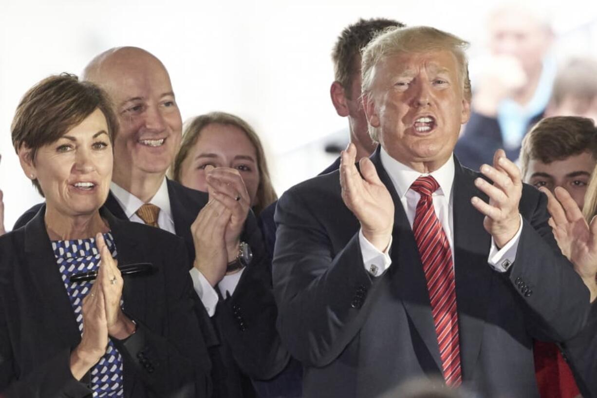 In this June 11, 2019 photo, President Donald Trump applauds next to Governors Pete Ricketts of Nebraska, second left, and Kim Reynolds of Iowa, left, in Council Bluffs, Iowa. An executive order by Trump giving states the right to refuse to take refugees is putting Republican governors in an uncomfortable position. They&#039;re caught between immigration hardliners who want to shut the door and others who believe helping refugees is a moral obligation.