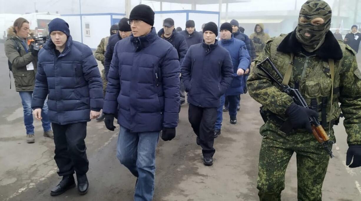 A Russia-backed separatist soldier escorts war prisoners after they were exchanged near the checkpoint Horlivka, eastern Ukraine on Sunday. Ukrainian forces and Russia-backed rebels in the east have begun exchanging prisoners in a move aimed at ending their yearslong war.