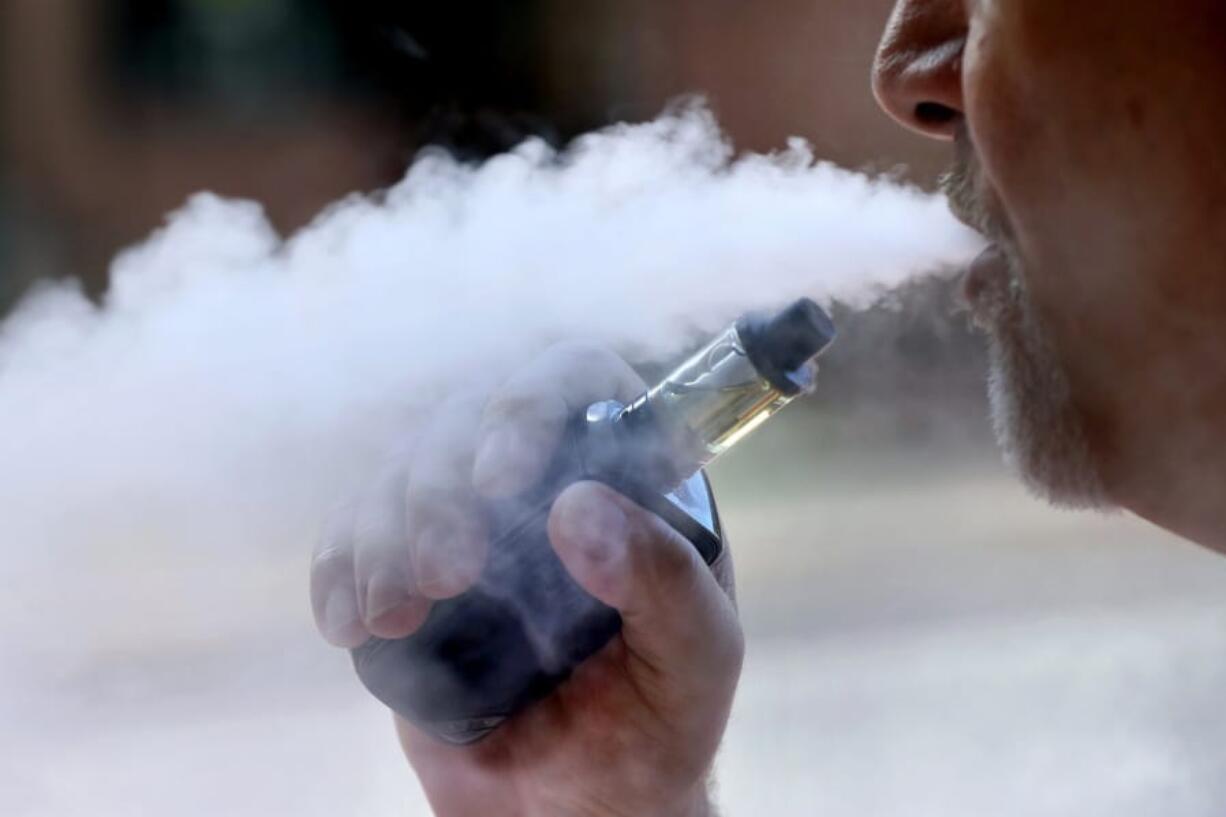 FILE - In this Aug. 28, 2019, file photo, a man exhales while smoking an e-cigarette in Portland, Maine. Health officials investigating a nationwide outbreak of vaping-related illnesses have, for the first time, listed the vape brands that are most commonly linked to hospitalizations. Most of the nearly 2,300 people who has suffered lung damage were vaping liquids that contain THC, the high-inducing part of marijuana. In a report released Friday, Dec. 6 the government listed the THC-containing products that patients most often said they&#039;d been using, noting that some patients vaped more than one. (AP Photo/Robert F.