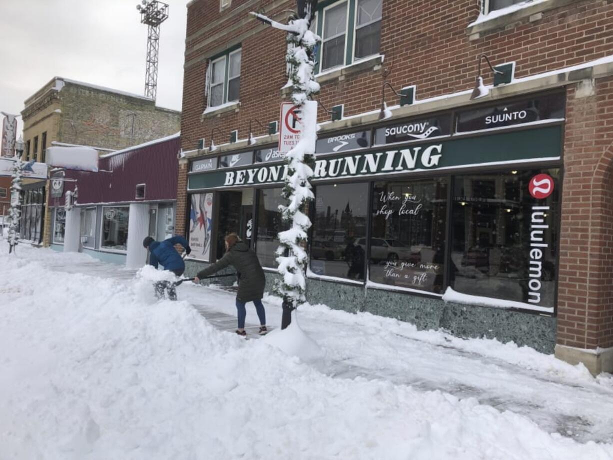 Jake Olson, left, and Mackenzie Weinberger shovel snow outside of a store in downtown Fargo, N.D., on Monday following a blizzard that dropped over a foot of snow in the area and closed streets, highways and many businesses.