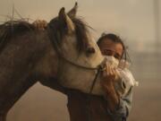 Fabio Losurdo comforts his horse, Smarty, at a ranch in Simi Valley, Calif., on Oct. 30. A brush fire broke out just before dawn in the Simi Valley area north of Los Angeles. (AP Photo/Ringo H.W.