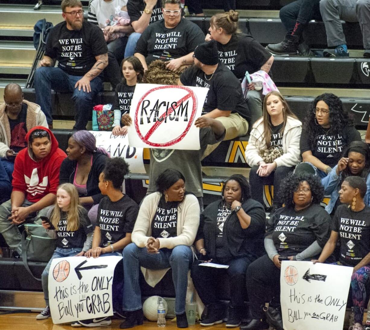 Spectators at Hudson&#039;s Bay on Friday hold signs and wear T-shirts protesting against racial taunts basketball players say they received at a game earlier this season in Kelso.