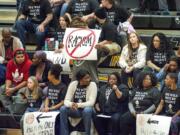 Spectators at Hudson&#039;s Bay on Friday hold signs and wear T-shirts protesting against racial taunts basketball players say they received at a game earlier this season in Kelso.