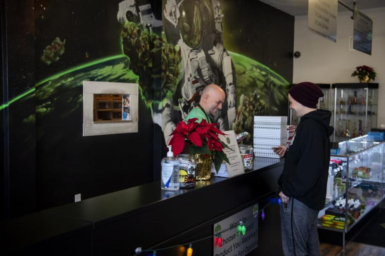 Charlie Gregory, budtender and cashier, helps Briana Reed of Vancouver finish her purchase at Main Street Marijuana in Vancouver on Dec. 12.