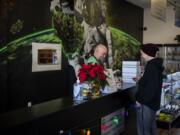 Charlie Gregory, budtender and cashier, helps Briana Reed of Vancouver finish her purchase at Main Street Marijuana in Vancouver on Dec. 12.