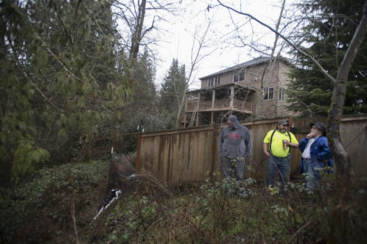 J.R. Ramsey, from left, and Guy Price of Advanced Earth Stabilization consult with homeowner Richard Schwartz of Ridgefield about the landslide in his backyard. Schwartz has been trying to get his yard fixed for more than two years after heavy rain and a neighboring stormwater pond caused a landslide on the hill behind his house.