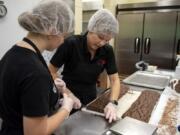 Killa Bites baker Teija Karlsen, 16, and Killa Bites co-owner Donna Suomi cut biscotti in Ridgefield. Suomi is working with employees to teach them recipes and instructions. Suomi hopes to be more hands-off in the kitchen so she can spend more time developing recipes.