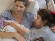 Tia Purviance holds her newborn daughter, Evaine Josephina, while sister Allie leans in to see the new baby. Evaine was the first baby born in Clark County in 2020, entering the world at 4:41 a.m. at PeaceHealth Southwest Medical Center&#039;s Family Birth Center.