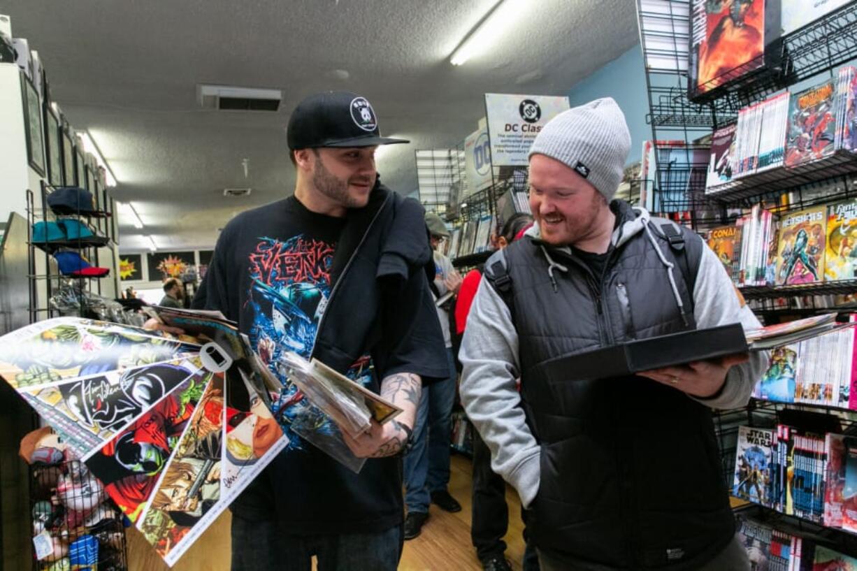 Vancouver resident Bryan West, left, shows Nick Bishop of Vancouver his signed comic books at the Image Comics partner signing event at I Like Comics in Vancouver. The signing featured the creator of &quot;Spawn&quot; and &quot;The Walking Dead&quot; comic books, and drew more than 900 people.