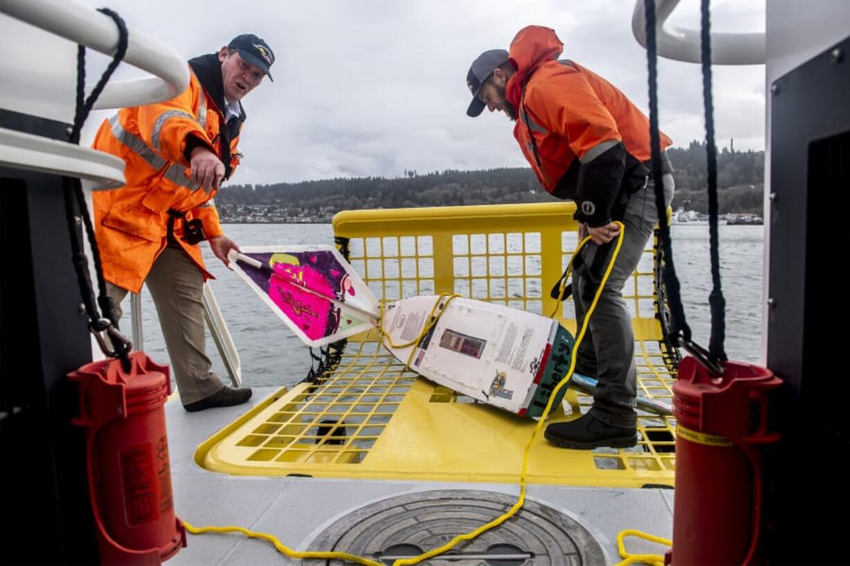 Bar pilot captain Dan Jordan, left, and deck hand Tyler Bartel pull the S/V Liberty miniboat from the Columbia River following a test launch in Astoria, Ore., on Tuesday afternoon.