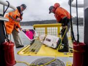 Bar pilot captain Dan Jordan, left, and deck hand Tyler Bartel pull the S/V Liberty miniboat from the Columbia River following a test launch in Astoria, Ore., on Tuesday afternoon.