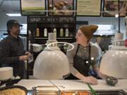 Steve Valenta, left, owner of The Mighty Bowl in downtown Vancouver, talks with employee Elias Gribble while preparing for the lunch rush on Wednesday. Gribble is one of the employees who recently received a minimum-wage increase.