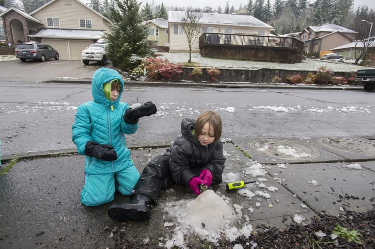 Finn Mullenberg, 6, left, of Washougal joins his sister, Lily, 8, as they try to make the most of the slushy, thawing snow near their home Thursday morning. The pair were among the students in Clark County who had the day off because of winter weather.