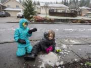 Finn Mullenberg, 6, left, of Washougal joins his sister, Lily, 8, as they try to make the most of the slushy, thawing snow near their home Thursday morning. The pair were among the students in Clark County who had the day off because of winter weather.