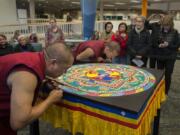 LEADOPTION
Jampa Tenzin, left, and Ngawang Shakya, Tibetan Buddihist monks, attract a crowd while adding the finishing touches to a sand mandala at Clark College on Friday afternoon.  According to Tibetan Buddhist belief, a sand mandala is meant to create a profound experience of compassion for any who attend. (Amanda Cowan/The Columbian)