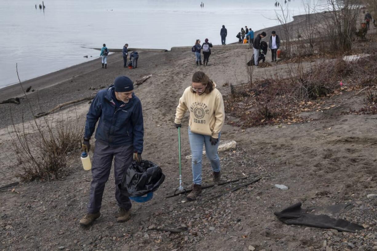 Bob Cather, left, and Claire Berhein search for trash along the Columbia River during Monday&#039;s Martin Luther King Jr. Day beach cleanup.