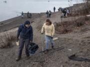 Bob Cather, left, and Claire Berhein search for trash along the Columbia River during Monday&#039;s Martin Luther King Jr. Day beach cleanup.