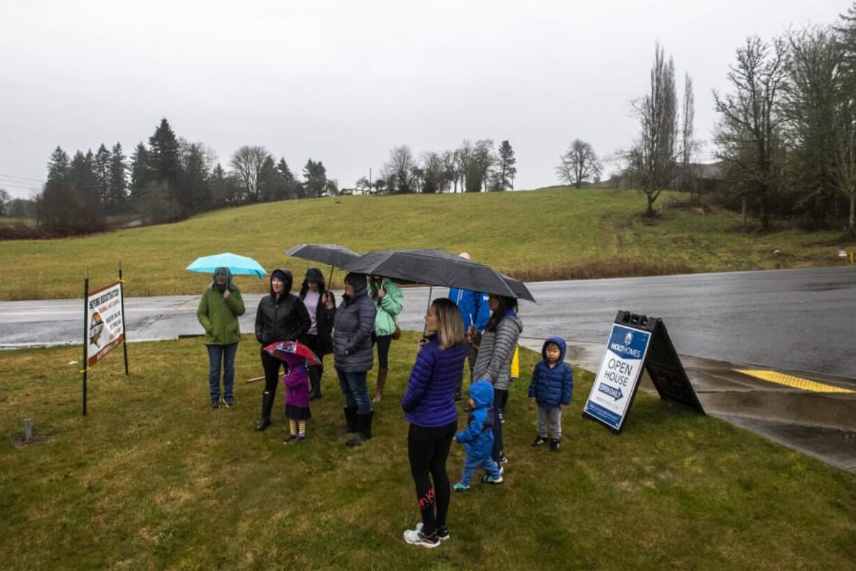 A group opposed to a proposed Verizon cell tower meets Thursday in front of the land where the tower would be built, across the street from Woodburn Elementary School.