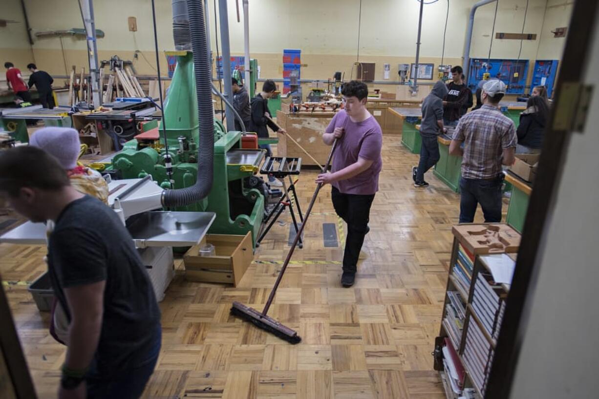 Ridgefield High School sophomore Koel Hibner, 16, center, helps keep the wood shop room in top shape while working with classmates during wood tech class Thursday afternoon. The district is considering converting the building where the wood shop is located into a warehouse space, which the district doesn&#039;t currently have.