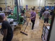 Ridgefield High School sophomore Koel Hibner, 16, center, helps keep the wood shop room in top shape while working with classmates during wood tech class Thursday afternoon. The district is considering converting the building where the wood shop is located into a warehouse space, which the district doesn&#039;t currently have.