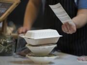 Workers arrange to-go meals in biodegradable take-out boxes and containers at The Mighty Bowl. The popular downtown Vancouver eatery is stopping its use of single-use plastic items and will only use recyclable or compostable items.