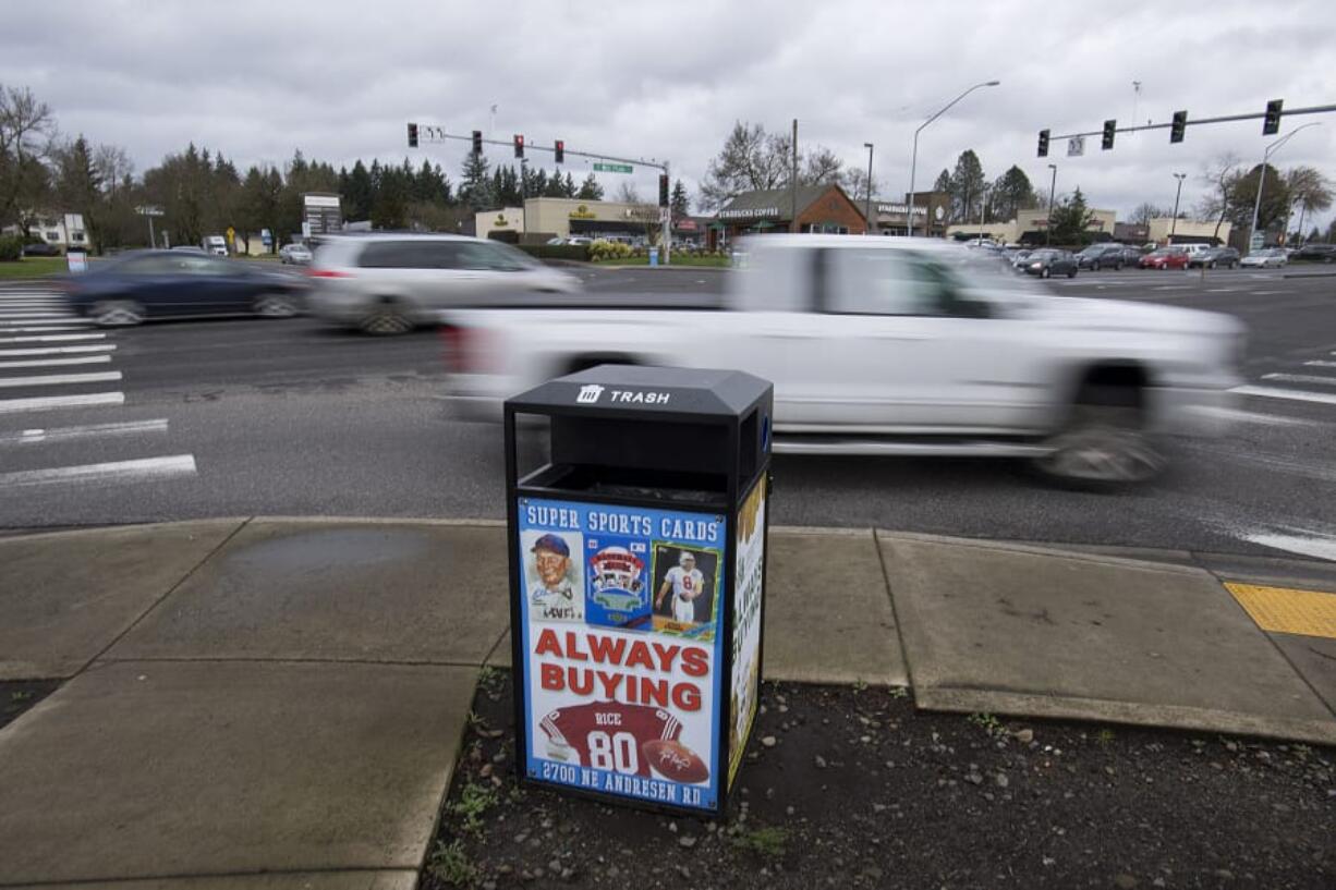 Motorists travel past a receptacle for garbage and recycling with advertisements at the corner of Southeast Chkalov Drive and Southeast Mill Plain Boulevard on Friday morning.