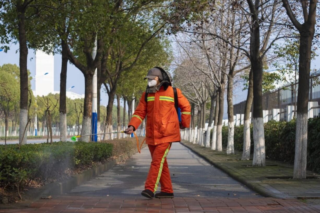 A worker wearing a face mask sprays disinfectant along a path in Wuhan in central China&#039;s Hubei Province, Tuesday, Jan. 28, 2020. China&#039;s death toll from a new viral disease that is causing global concern rose by 25 to at least 106 on Tuesday as the United States and other governments prepared to fly their citizens out of the locked-down city at center of the outbreak.